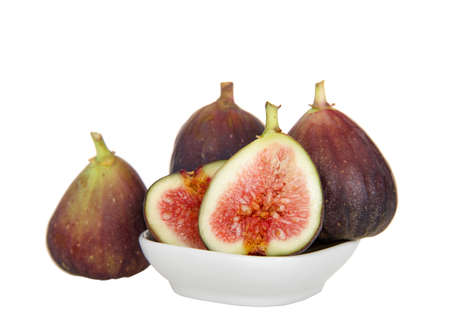 Fresh organic figs in and around a small white bowl, one sliced in half showing inside. Isolated on white.の写真素材