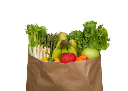 Top of brown paper grocery bag stuffed full with fruits and vegetables. Celery, white and green asparagus, bananas, lettuce, yellow bell pepper, red and green apples, clementines and a pear. Isolated.の写真素材