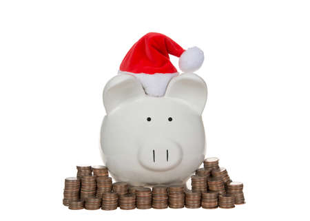 White porcelain piggy bank wearing Santa hat surrounded by stacks of coins, quarters. Isolated on whiteの写真素材