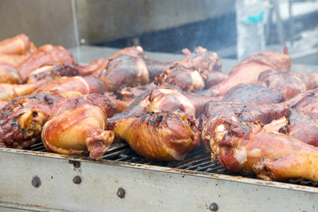 BBQ chicken lined up on a large outdoor grill with smoke coming up from the fire below.の写真素材