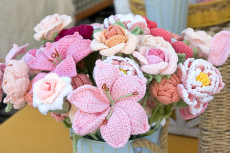 Close up on bouquet of hand crafted crochet flowers in a vase on a wood table. Various varieties.の写真素材