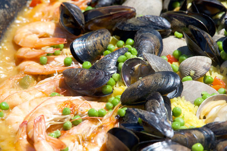 Close up on clams, muscles, shrimp rice and peas cooking in a giant outdoor wok. Mexican seafood dish called Paellaの写真素材