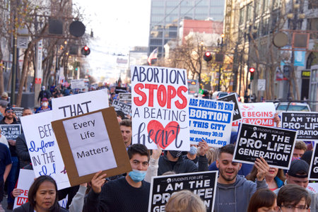 San Francisco, CA - Jan 23, 2021: Unidentified participants at the 17th annual Walk for Life marching down Market street holding pro life signs and banners. People wearing masks, some people not.のeditorial素材