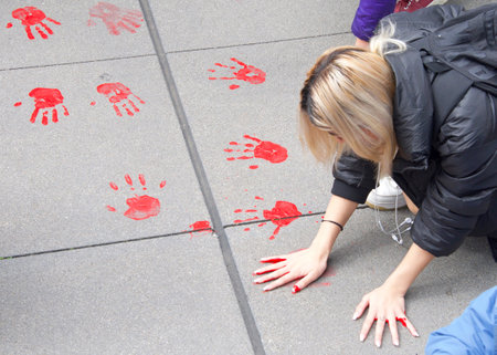 San Francisco, CA - March 25, 2022: Youth lead climate strike participants placing red painted hand prints on the sidewalk in front of Sales Force Towers in protest of Fossil Fuels and Climate Changeのeditorial素材