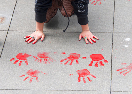 San Francisco, CA - March 25, 2022: Youth lead climate strike participants placing red painted hand prints on the sidewalk in front of Sales Force Towers in protest of Fossil Fuels and Climate Changeのeditorial素材