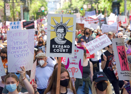 San Francisco, CA - May 14, 2022: Unidentified participants marching in the streets holding signs in...