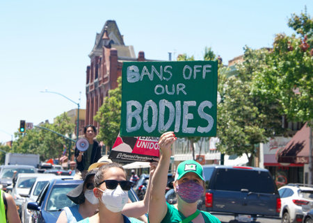 Alameda, CA - July 10, 2022: Youth Led Protesters holding signs protesting SCOTUS overturning Roe, removing abortion rights. Yelling while walking down commercial area on Park Street to City Hall for a rallyのeditorial素材