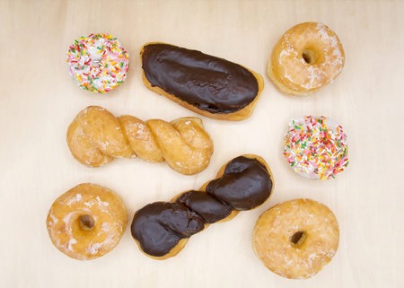 Flat lay top view of variety of donuts. Chocolate and Glazed twists, frosted cake sprinkles with...