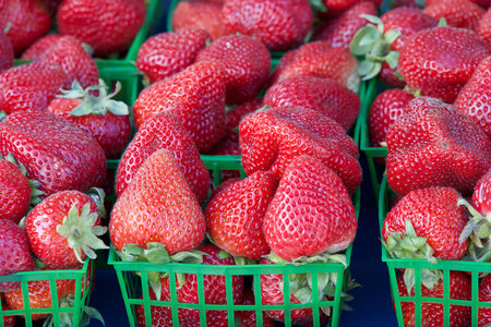 Close up on baskets heaped full of fresh ripe strawberries sale at farmers market..の写真素材