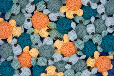 Close up above view on hand made crochet turtles in yellow and orange and greens and turquoise an blue crochet background.の写真素材