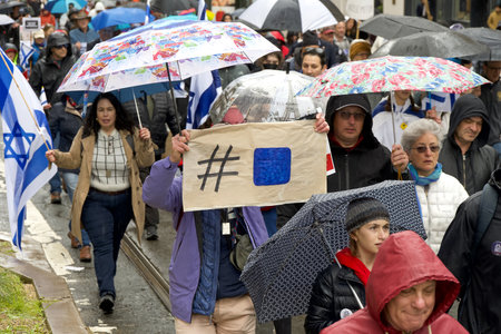 San Francisco, CA - March 03, 2024: Unidentified participants in a March Against Anti-Semitism up Market Street to Civic Center. Marching in the rain.のeditorial素材