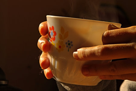 Hands holding a cup of hot tea with smoke