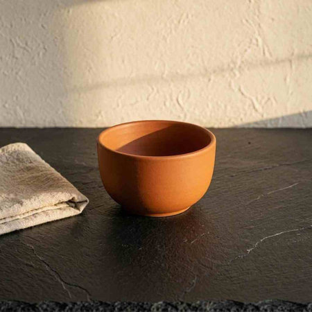 Ceramic bowl and towel on a black stone table in sunlight