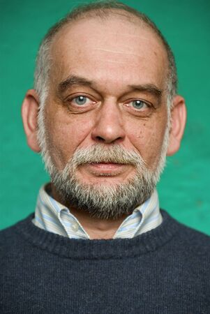 Portrait of the elderly man on green background.