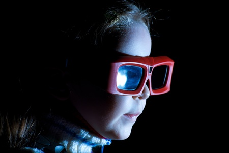 Beautiful little girl watching 3d movie. Isolated on black background.の写真素材