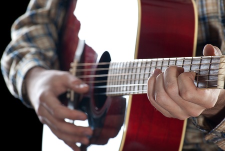 Closeup. Man playing guitar on black background.