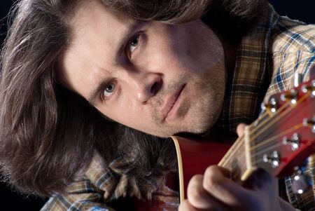 Guitarist. Closeup shoot of man with long hair plaing on a acoustic guitar.の写真素材