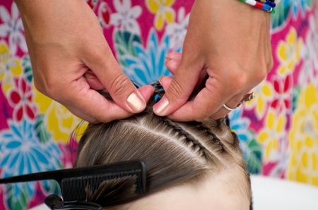 Hairdresser hands weaving a dreadlocks for little girl.の写真素材
