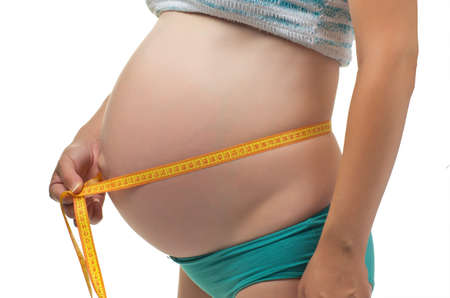 Pregnant woman measures her belly. Isolated on white background