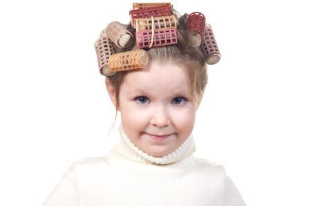 Beautiful little girl with curlers on her head. Isolated on white background.の写真素材