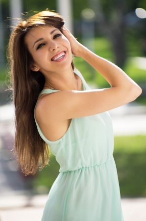 Beautiful caucasian brunette young woman in soft light green dress standing in the city square.の写真素材