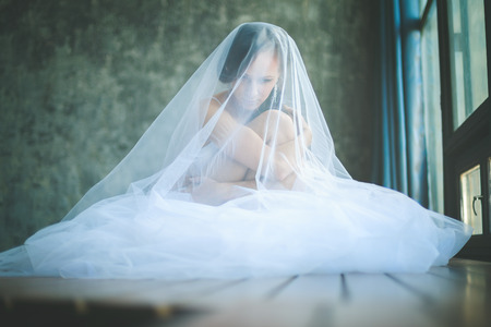 Portrait of young caucasian bride in lingerie sitting on the wooden floorの写真素材