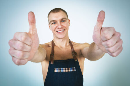 A shoot of young caucasian naked men in apron as a barmen. Showing the sign good, thumbs up.の写真素材