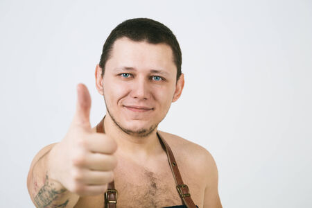 A shoot of young caucasian naked men in apron as a barmen. Showing the sign good, thumbs up.の写真素材