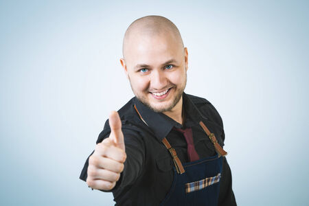 A shoot of young caucasian men in apron as a barmen. Showing the sign good, thumbs up.の写真素材