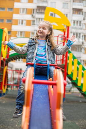 Girl in jeans suit swinging in a playgroundの写真素材