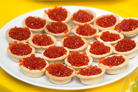 Red caviar in a tartlets on the plate over yellowの写真素材
