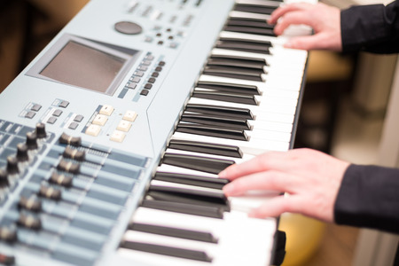 Male hands playing on the electronic pianoの写真素材