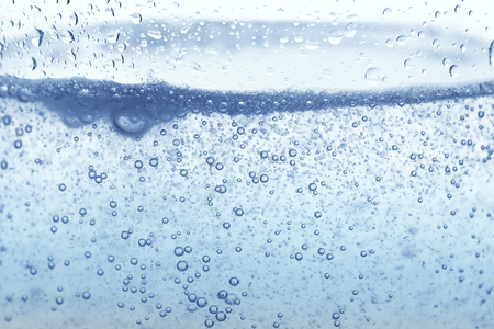 Bubbles of oxygen in glass of water on a blue background. Mineral water. background. Macro.Texture.の写真素材