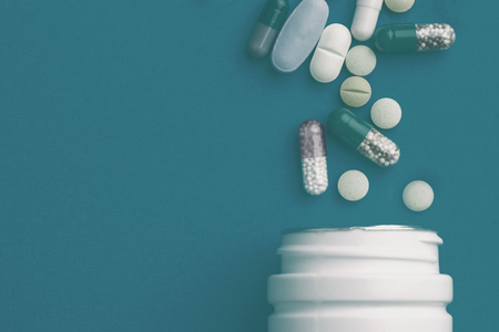 Assorted pharmaceutical medicine pills, tablets and capsules and bottle on green background. Copy spaceの写真素材