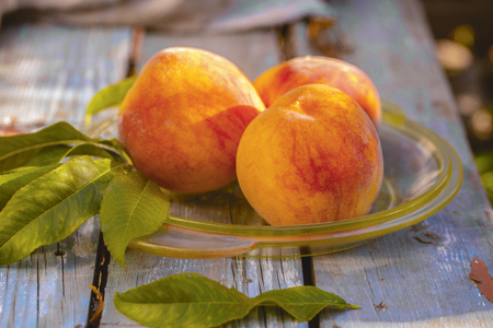 Plate with fresh sweet ripe peaches on old wooden tableの写真素材