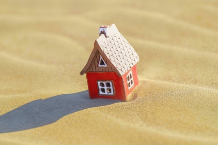Miniature toy house in the dry sandの写真素材