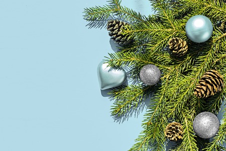 Christmas frame made of fir branches, festive decorations on blue wooden table. Christmas background. Flat lay. Top view with copy spaceの写真素材