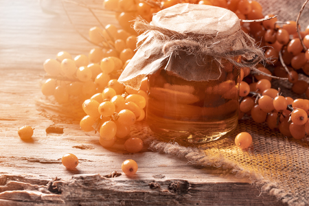 Branch of sea buckthorn with jam on table on sackcloth backgroundの写真素材