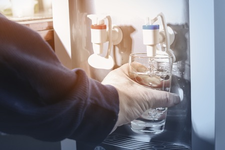 Male hand serving water of a water coolerの写真素材