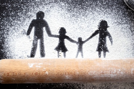 Figure flour in the form of family figures on a black table. Cooking pizza. The concept of family leisure.の写真素材