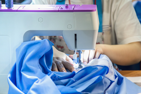 Female seamstress hands working on sewing machine