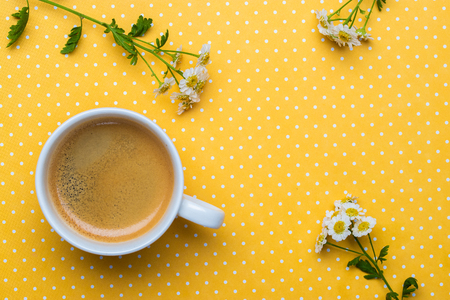 Chamomile flowers and a cup of coffee on a yellow polka dot background.の写真素材