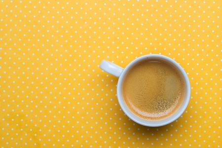 A cup of coffee on a yellow polka dot background.の写真素材