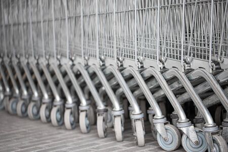 Shopping carts arranged in a row on the street near the supermarket.Close up wheel of shopping cart. Concept of shopping.の写真素材
