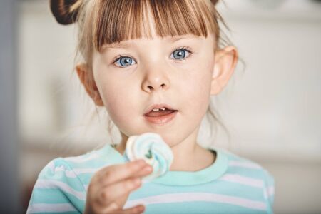 Nice little girl eats merengue.