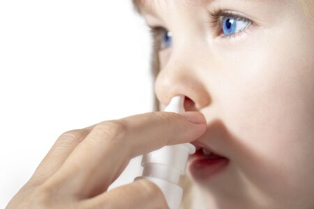 Mother using nose spray to cure her little girl Close up.の写真素材