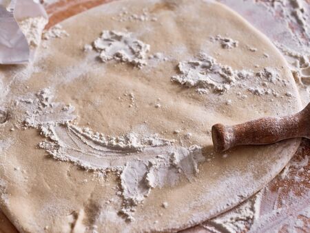 Piece of egg pasta dough rolled out on the table with the rolling pin.の写真素材