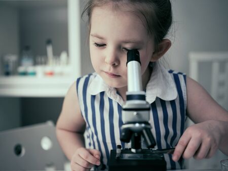 Little adorable girl makes scientific experiments with chemical and biological products in her home laboratory.の写真素材
