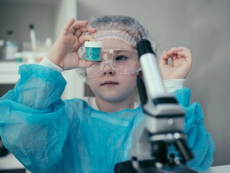 Little adorable girl makes scientific experiments with chemical and biological products in her home...
