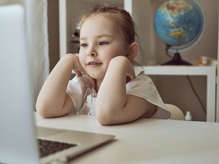 Cute little girl using laptop at home. Education, online study, home studying The girl at home...